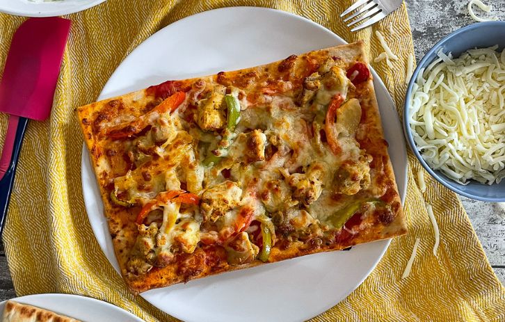 chicken tikka pizza on plate with salad.