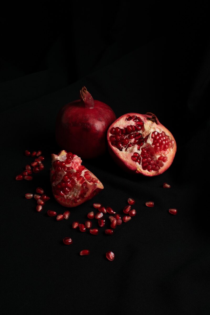 Pomegranate cut in half, seeds scattered.