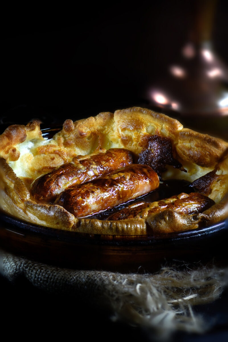 Pork sausages in Yorkshire pudding batter known as Toad In The Hole. Popular British dish when served with red wine onion gravy and steamed vegetables.