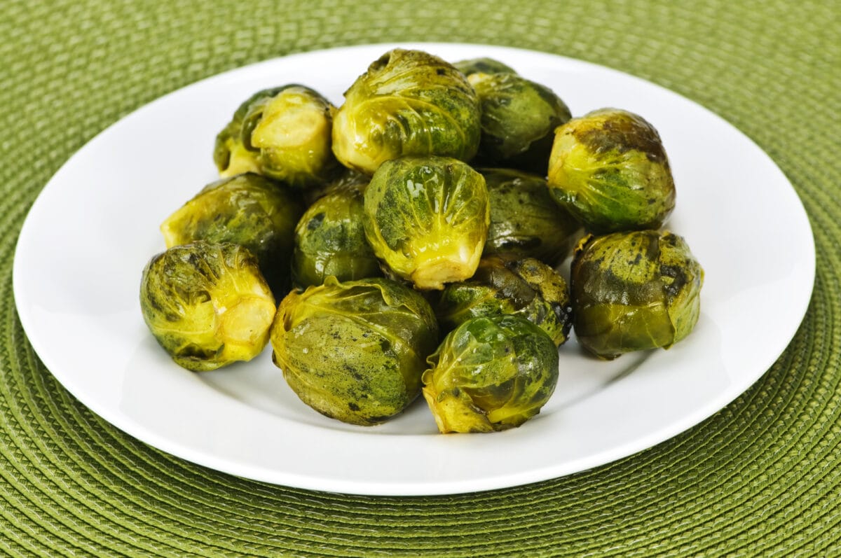 Plate of roasted green brussels sprouts on placemat.
