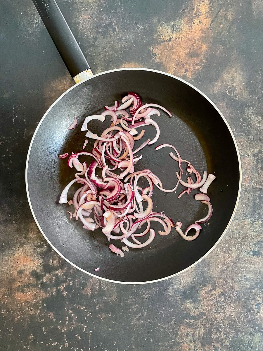 sliced red onion in frying pan.