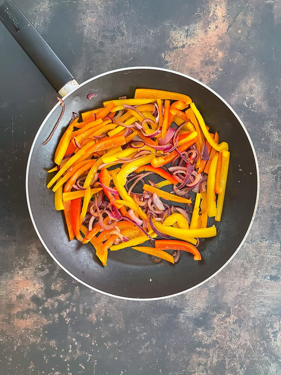 sliced onion and pepper in frying pan.
