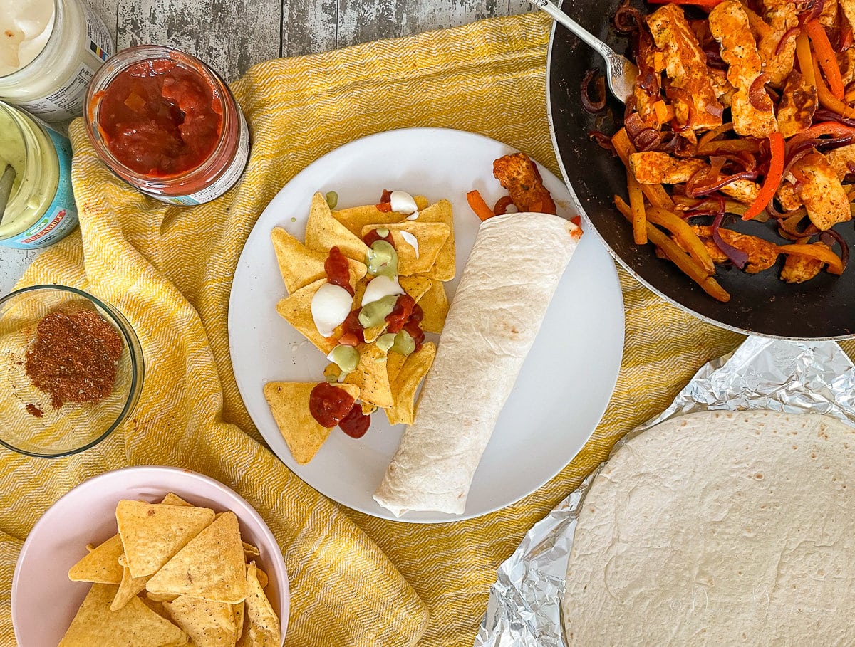 halloumi fajita on plate with chips and dips.