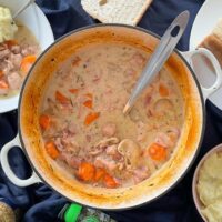 pork and cider casserole in cast iron dish with spoon.
