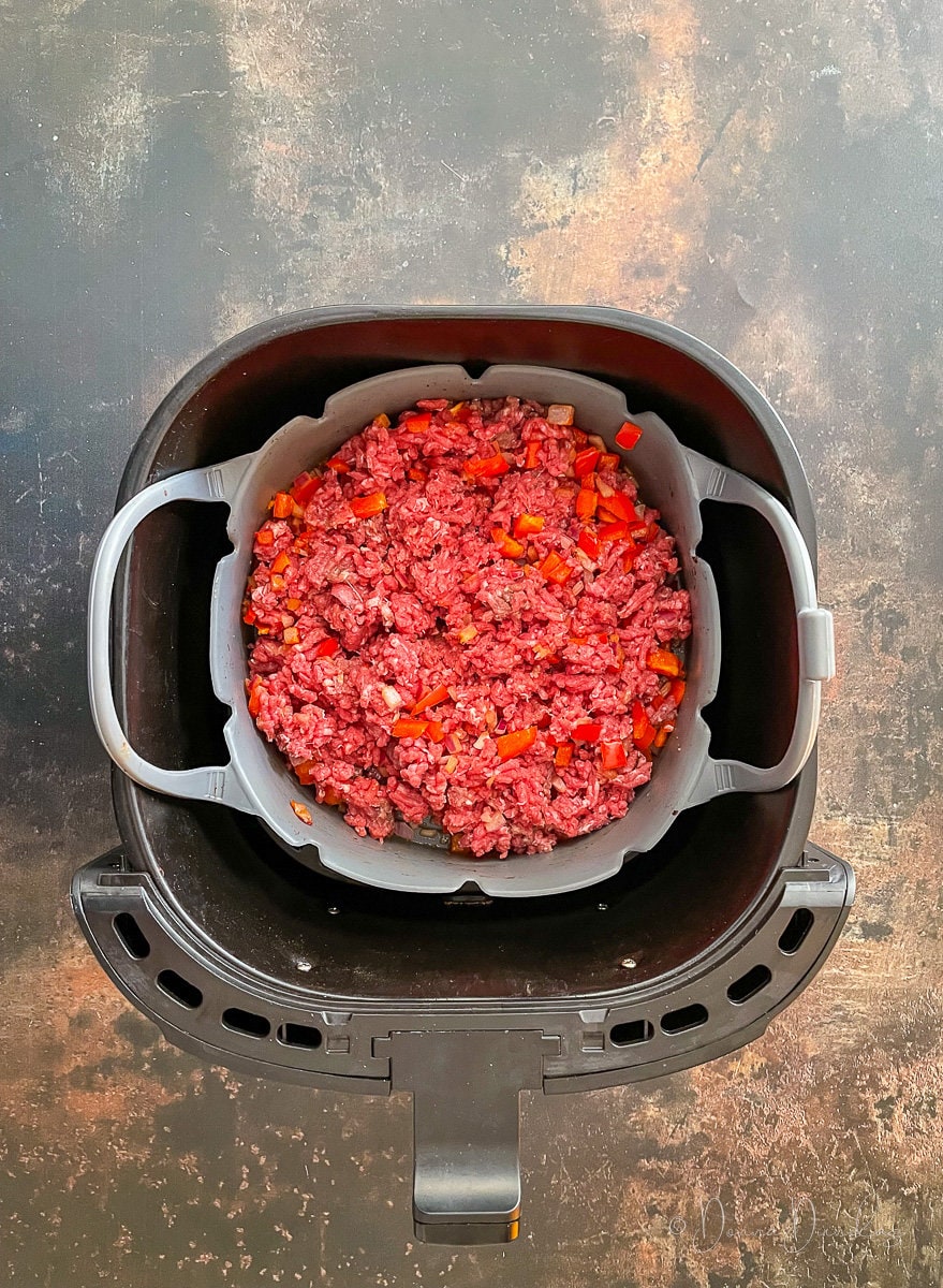uncooked mince in air fryer drawer.