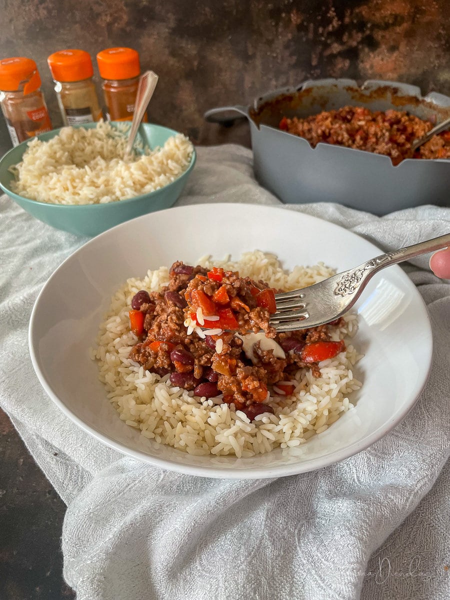 Served portion of air fryer chilli with rice topped with a dollop of soured cream.