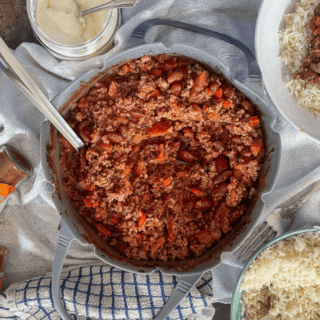 Air Fryer Chilli in silicone dish with serving spoon. Served potion to the side. Rice, soured cream and spices also on table.