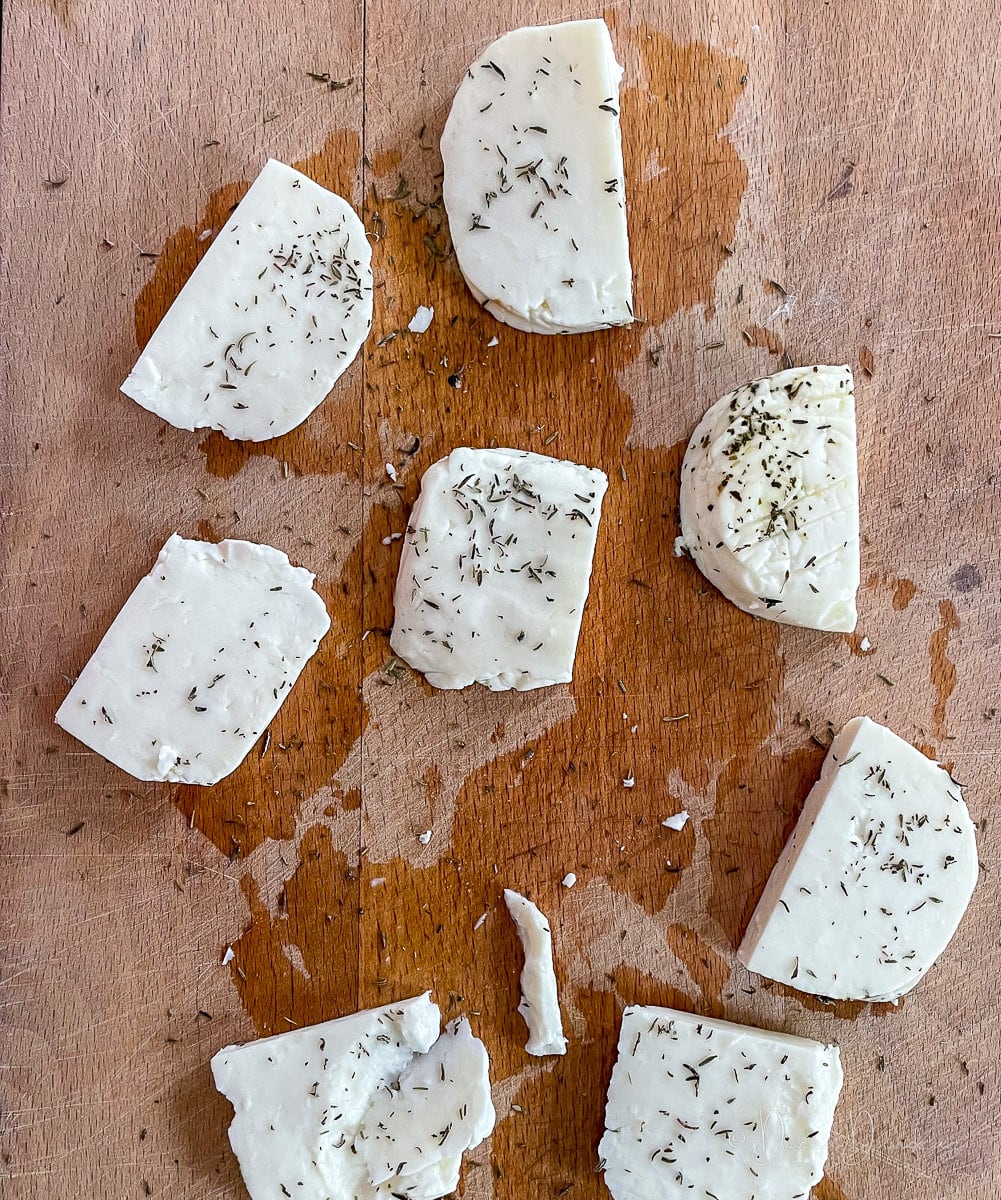 uncooked halloumi sprinkled with thyme on chopping board.
