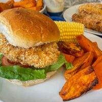 Air fryer crispy chicken burger with corn and sweet potato wedges.