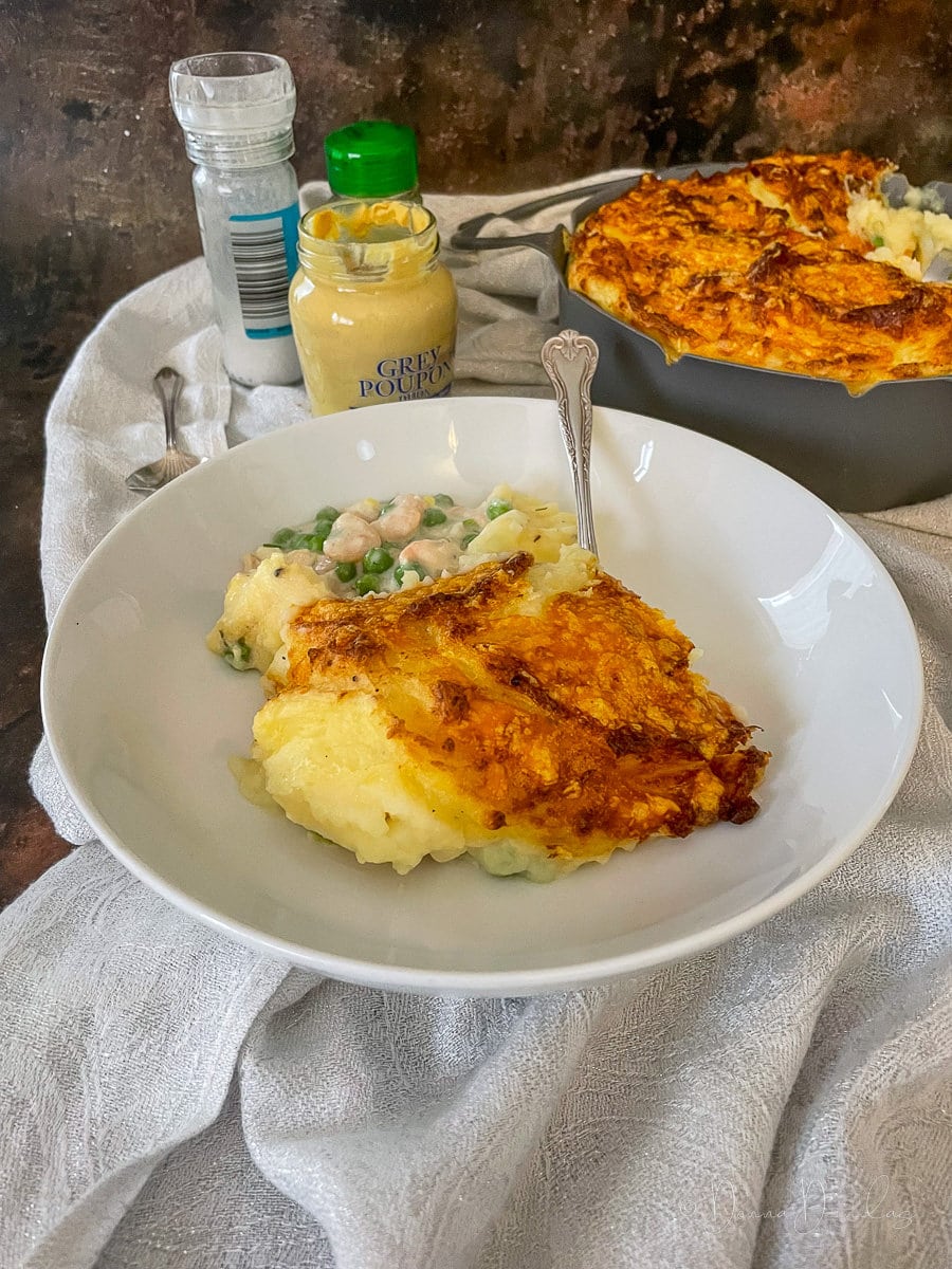 served portion of air fryer fish pie. Full pie in the background.