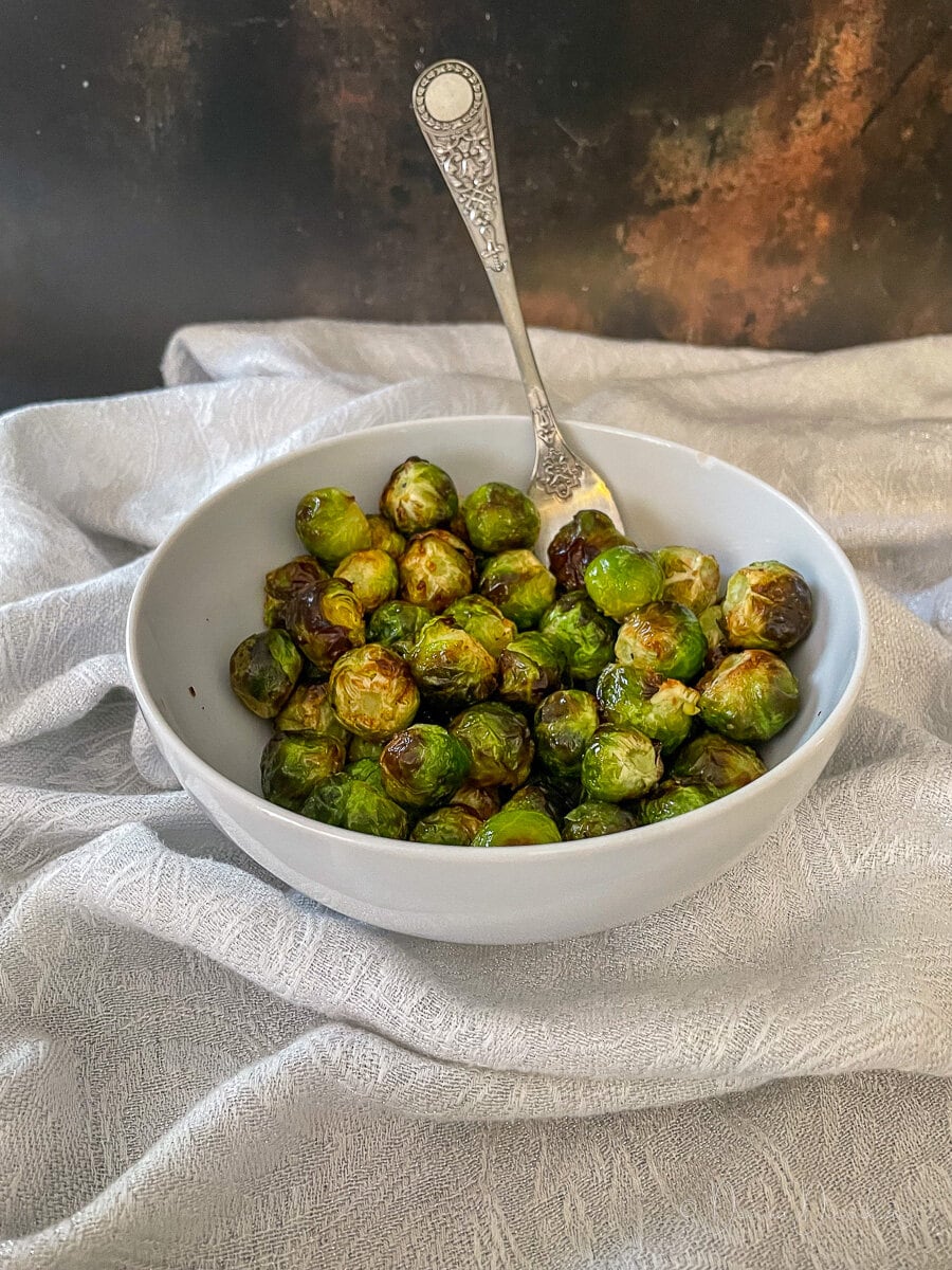 cooked sprouts in white bowl with fork.