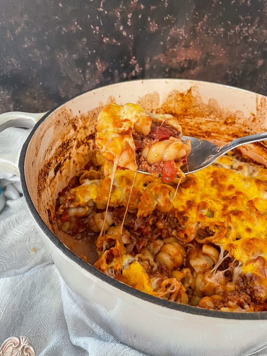 close up of cheesy pasta being lifted out of cooking dish.