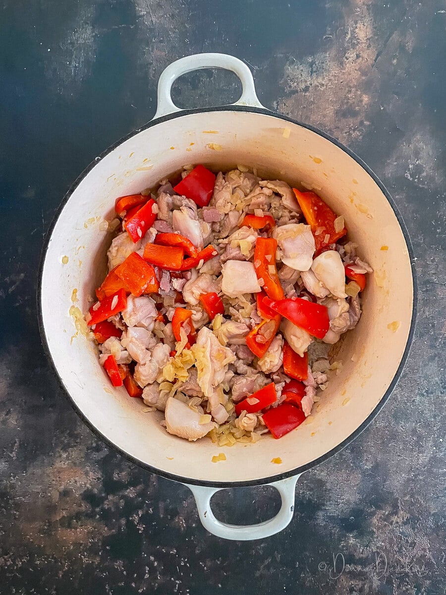 diced chicken thighs, bacon, onion and peppers in cast iron dish.