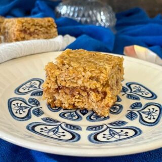 square of flapjack with jam in the middle on small blue patterened plate.