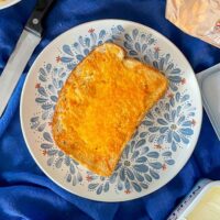Air Fried Tuna Melt topped with cheese on a blue patterned plate.