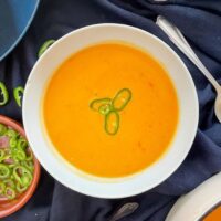 Served butternut squash and chilli soup in a white bowl, garnished with green chilli.