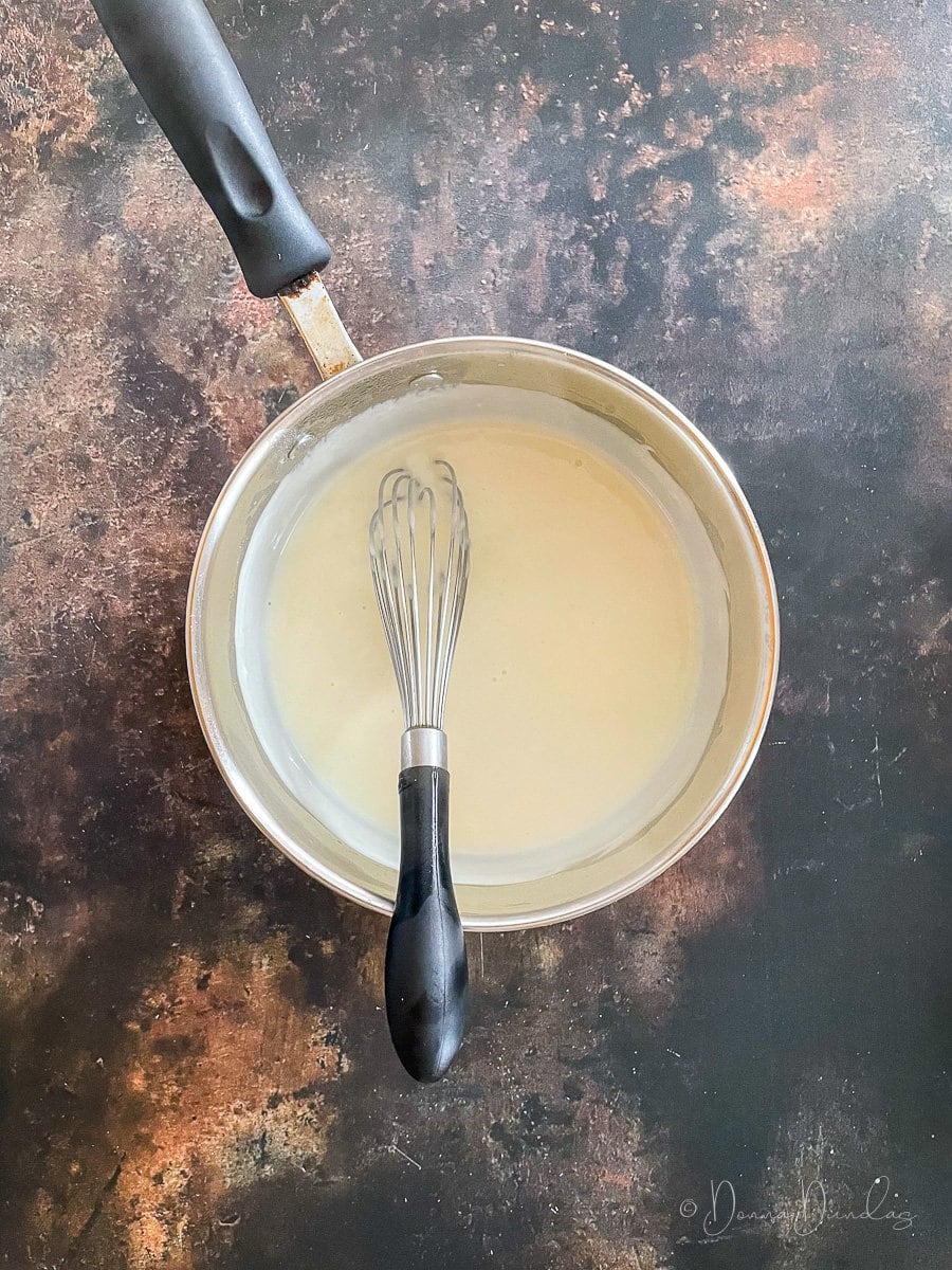 white sauce in pan with whisk.