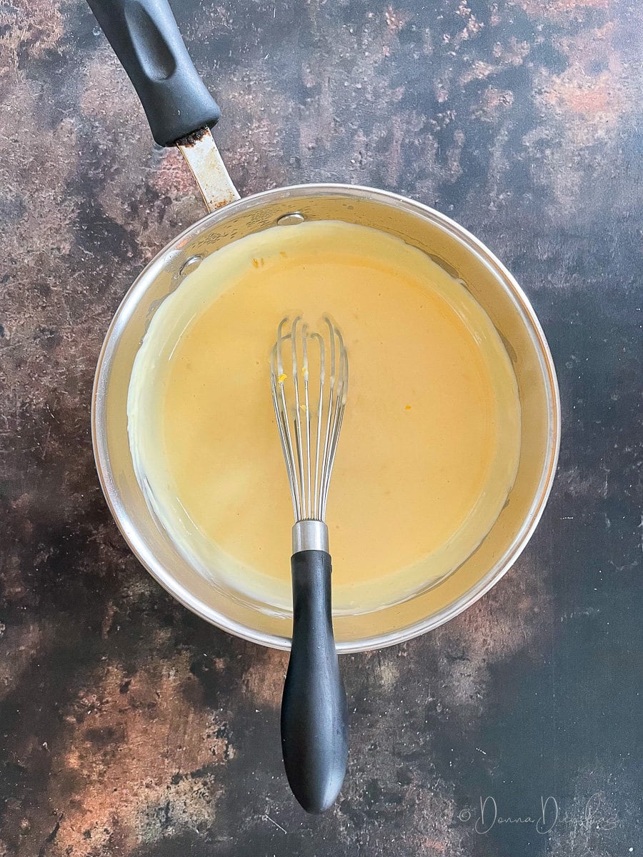 cheese sauce in saucepan with whisk.