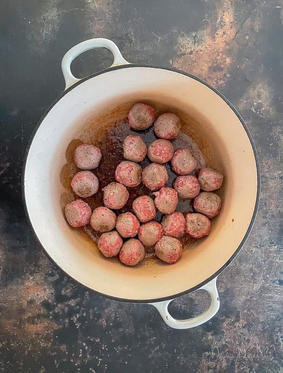 meatballs cooking in cast iron dish.
