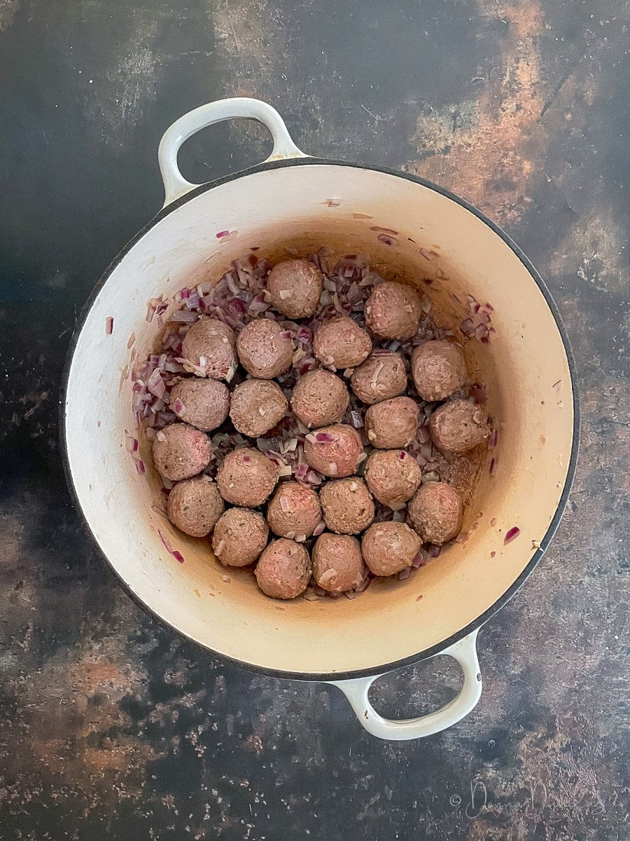 meatballs and onions in cast iron dish.