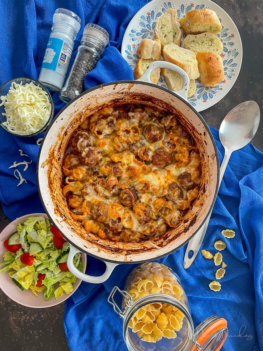 meatball pasta bake on table with salad and garlic bread.