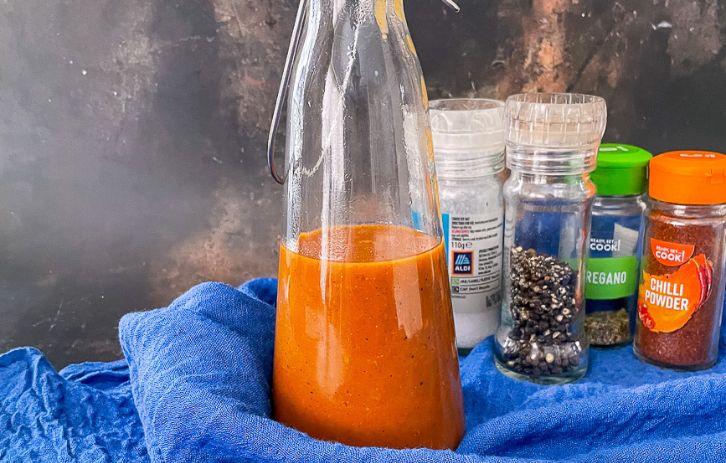 Bottle of Enchilada sauce with spices in the background.