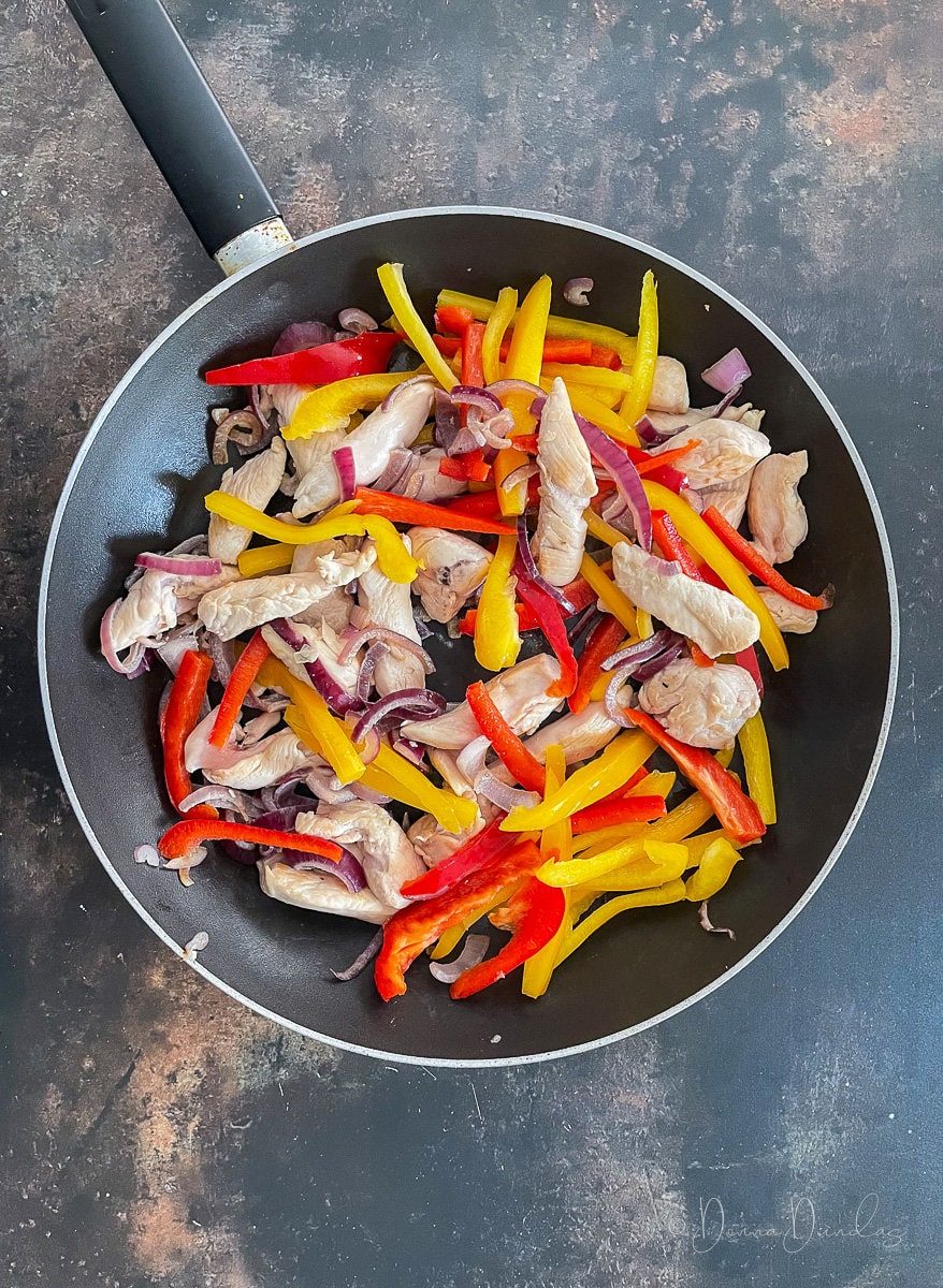 chicken, onions and peppers in pan.