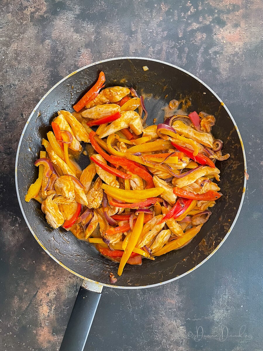chicken, onions, peppers and red sauce in pan.