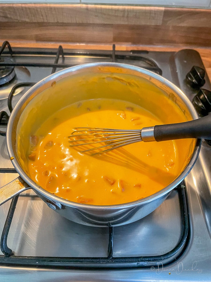 cheese sauce with chorizo in saucepan with whisk.