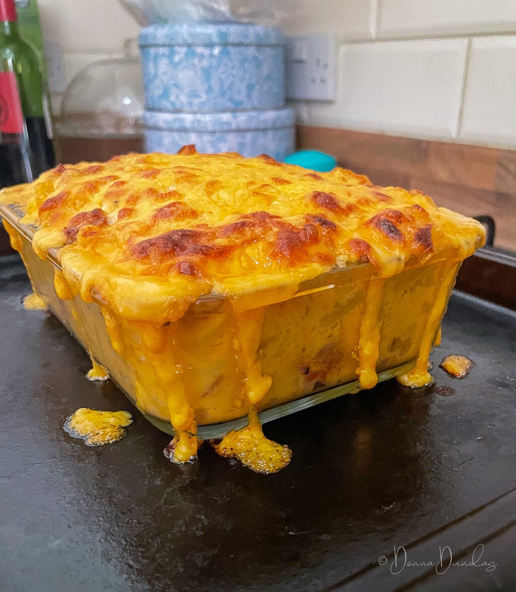 cooked chorizo Mac and cheese in glass dish, cheese running down the side.