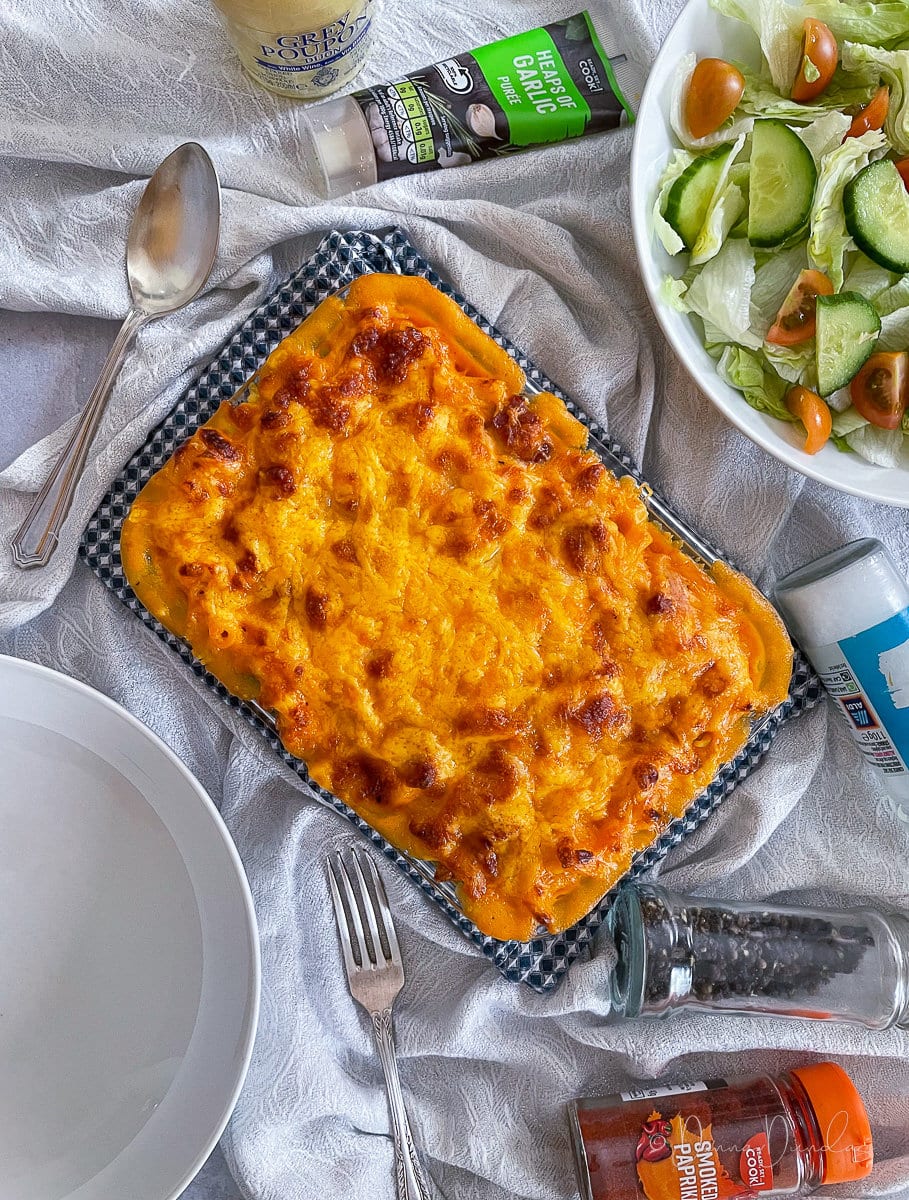 cheese topped dish on table with salad.