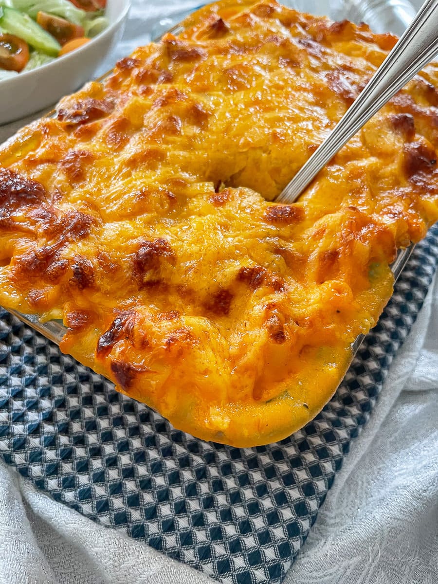 side view of chorizo mac and cheese with serving spoon sticking out.
