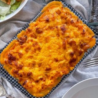 chorizo mac and cheese on table with salad and fork.