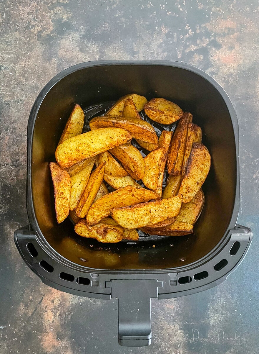 cooked wedges in air fryer basket.