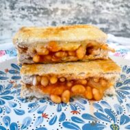 Air fryer cheese and bean toasties stacked on a blue patterned plate.