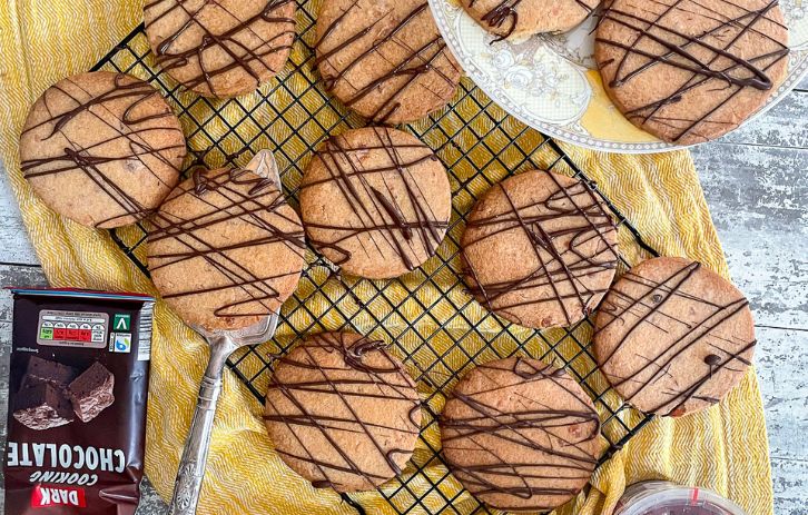 baked cherry shortbread cookies drizzled in chocolate on a wire rack.