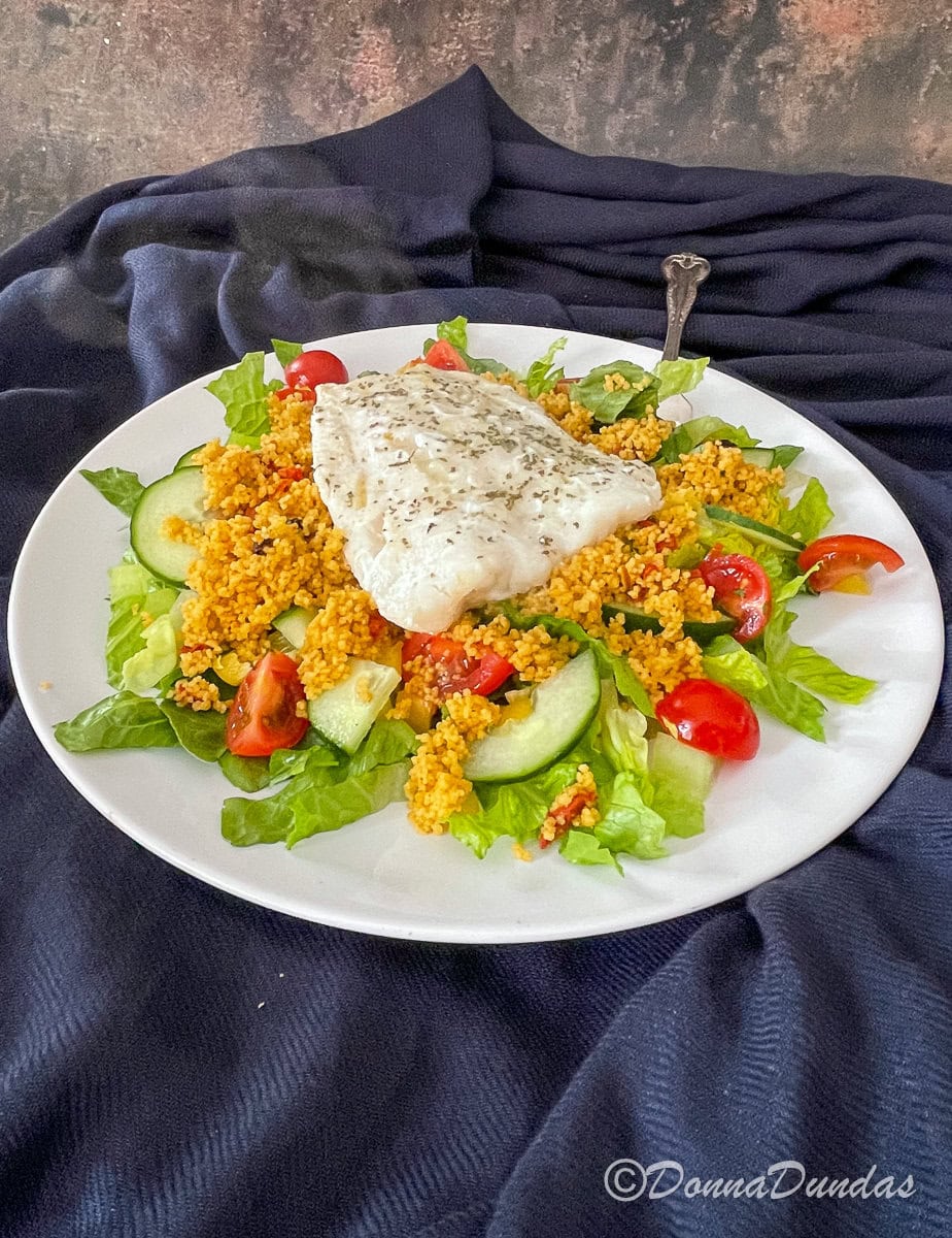 Air Fryer cod fillet on a bed of salad and couscous.