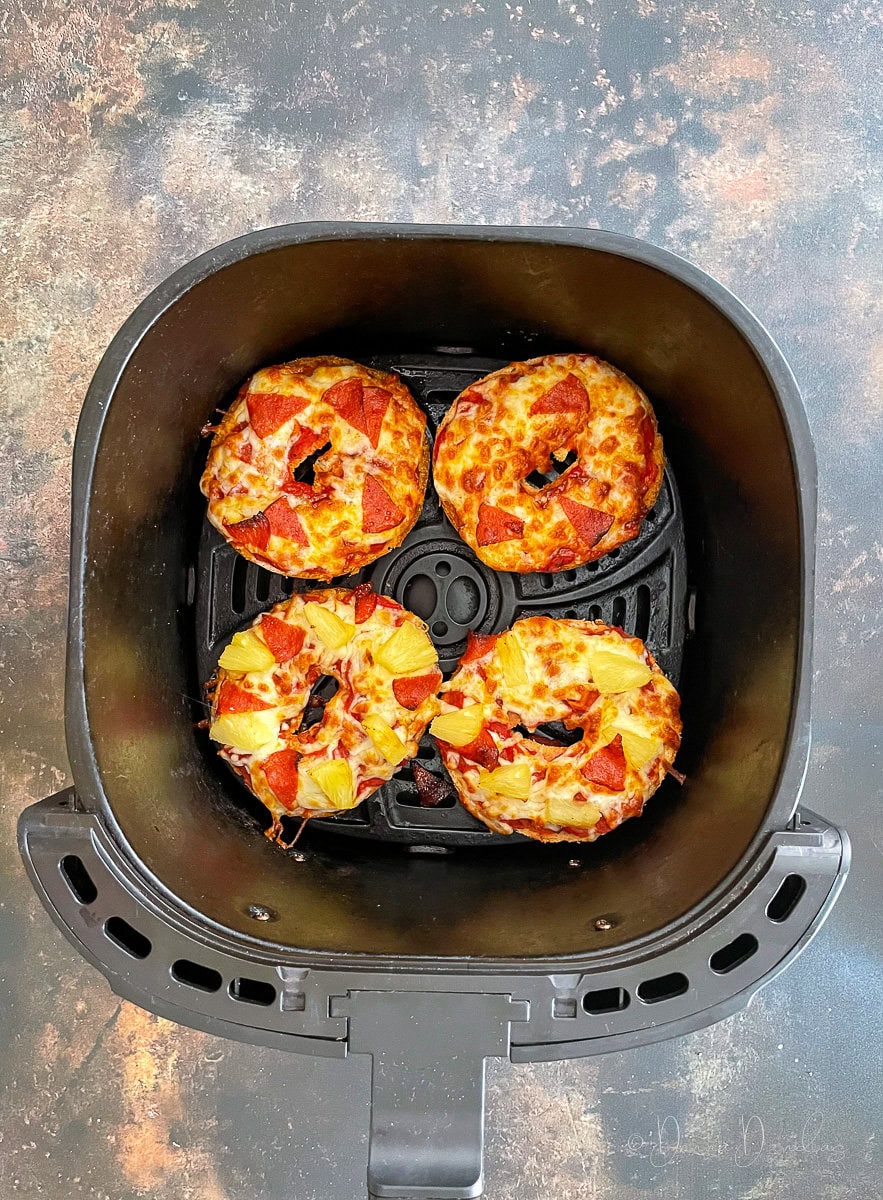 pizza bagels in air fryer basket.