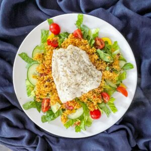 Air Fryer cod fillet on a bed of salad and couscous.