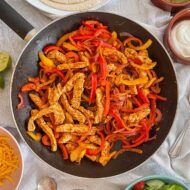 Close up of turkey fajita filling in frying pan. Strips of turkey, peppers, onions all visible.