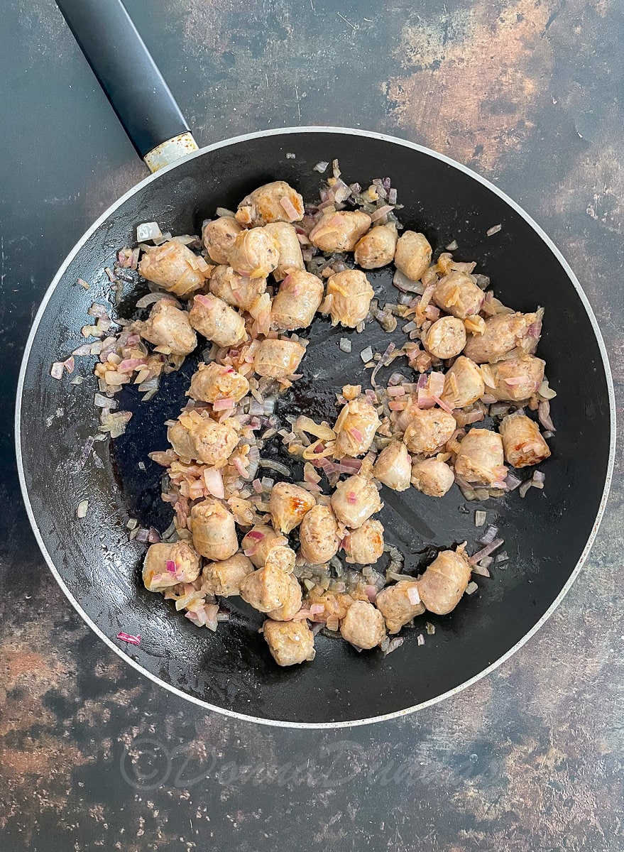 sausage pieces and onions in frying pan.