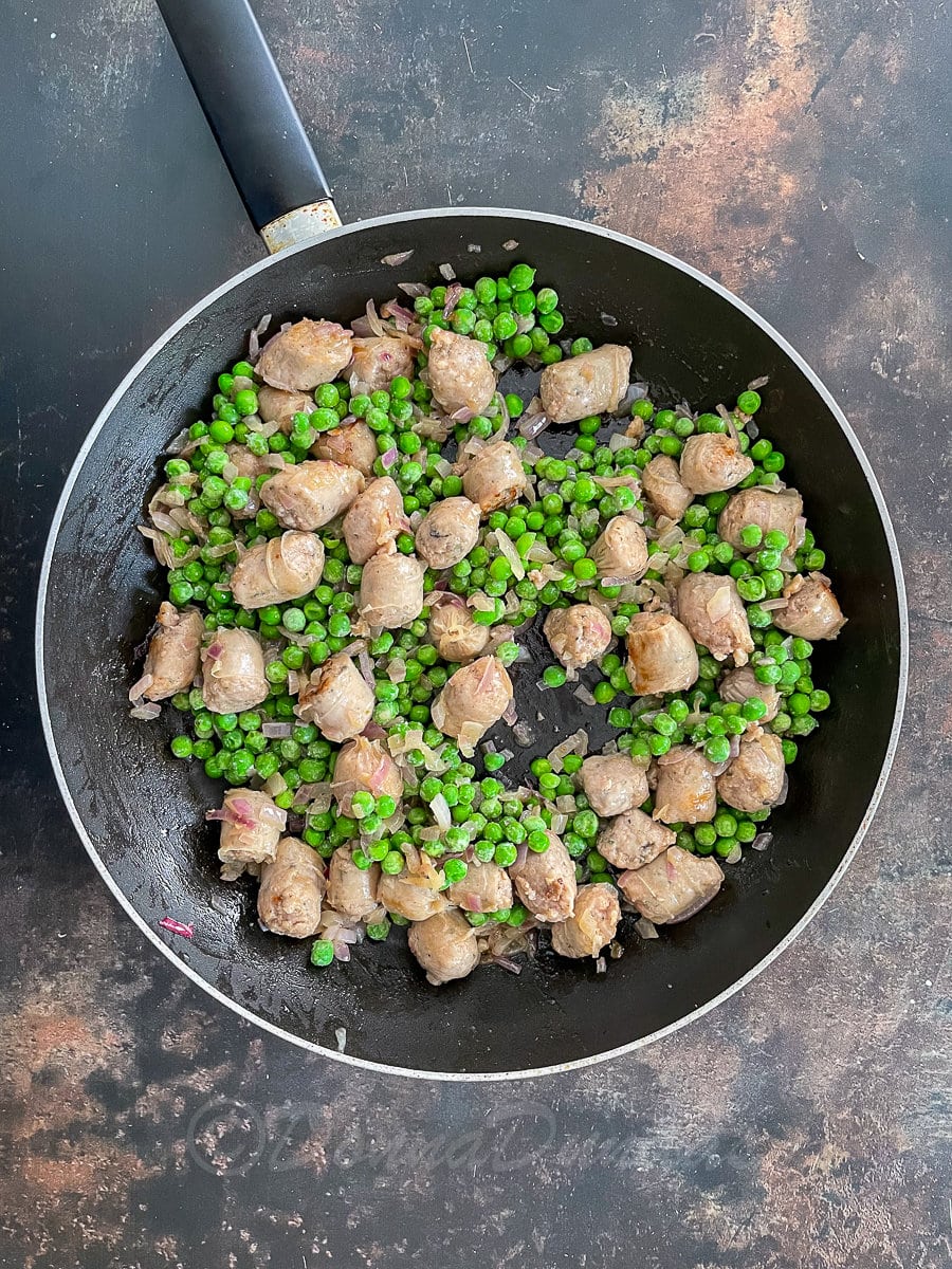 sausages, onions and peas in frying pan.
