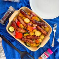 sausages, peppers, courgette and potatoes in cooking dish.