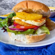 halloumi and pineapple on burger bun with lettuce, tomato and onion.