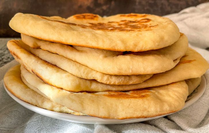 garlic naan bread stacked on plate.