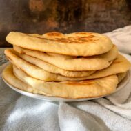 garlic naan bread stacked on plate.