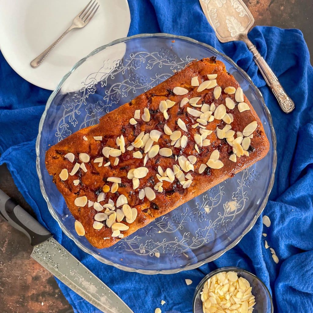 plum and almond loaf cake on glass cake stand.
