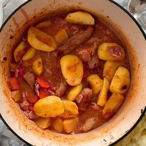 Sausage and apple casserole with cider in a cooking dish.