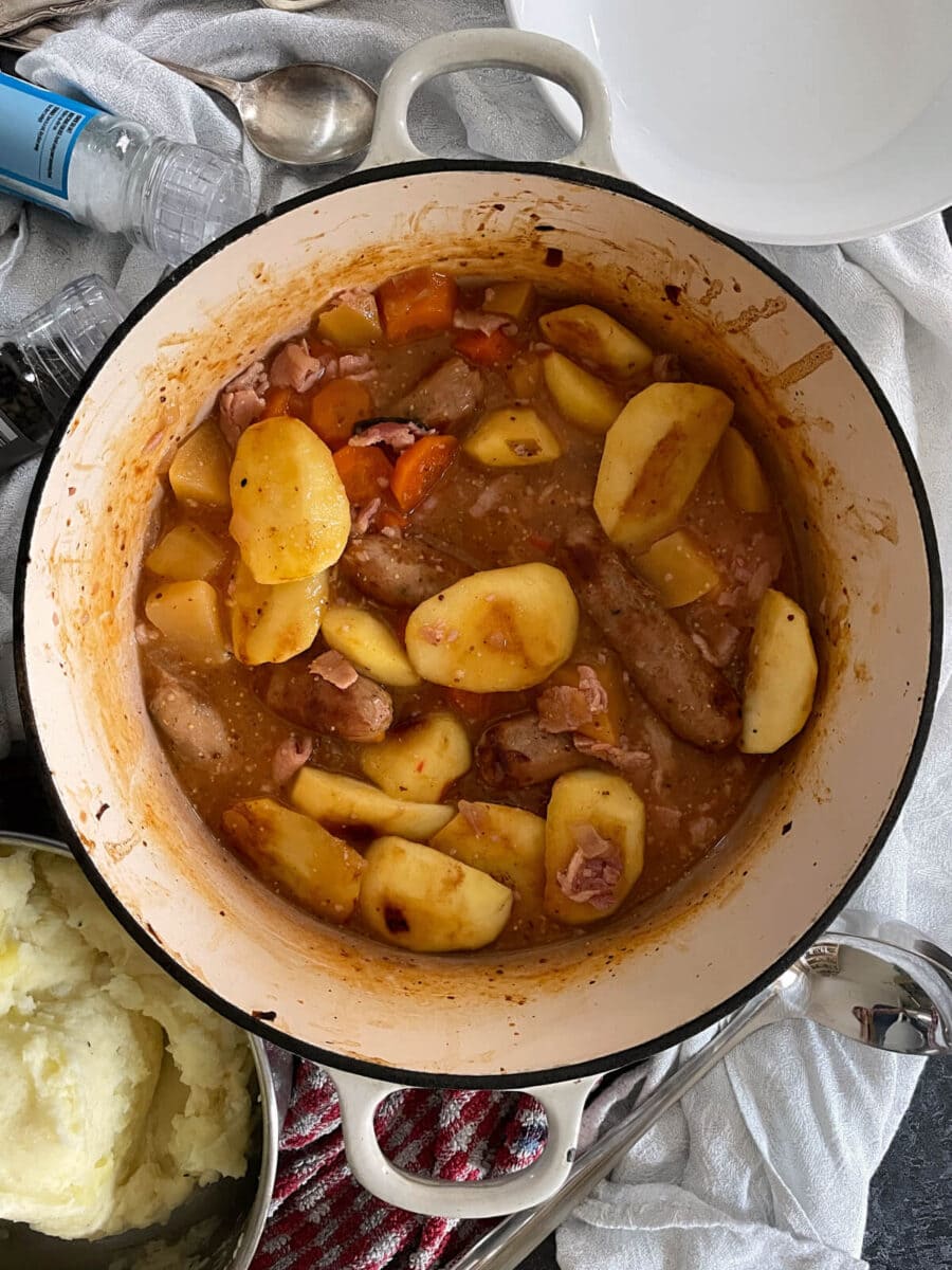 Sausage and apple casserole with cider in a cooking dish.