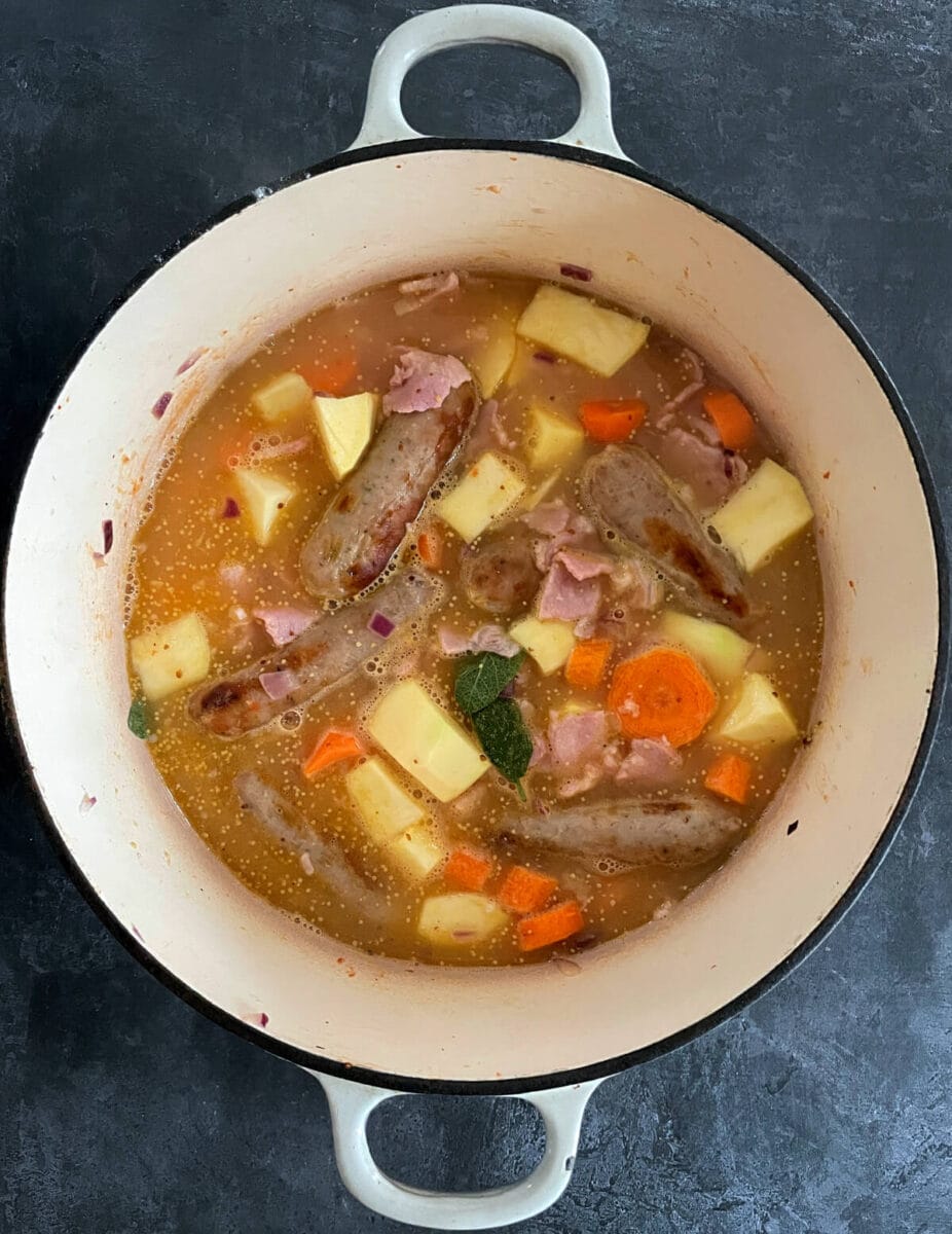 casserole with apples and sausages simmering in pan.